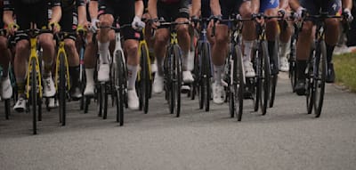 Zwei Radsportler kürzen ab und verstecken sich hinter einem Auto. Doch sie fliegen auf